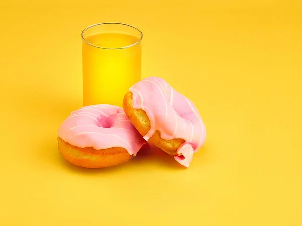 Os donuts e suco de laranja fresco no fundo amarelo — Fotografia de Stock