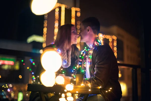 Pareja joven besándose y abrazándose al aire libre en la calle de la noche en Navidad —  Fotos de Stock