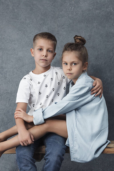 A portrait of little girl and a boy on the gray background