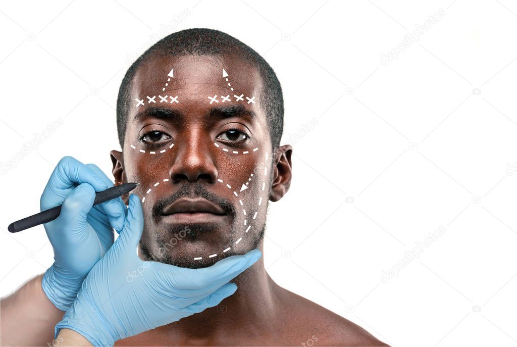Surgeon drawing marks on male face against gray background. Plastic surgery concept