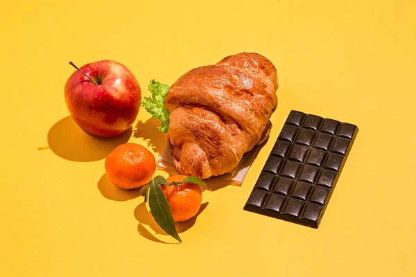 La mela, il cioccolato e i croissant su sfondo giallo — Foto Stock