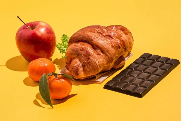 Яблоко, шоколад и круассаны на желтом фоне — стоковое фото