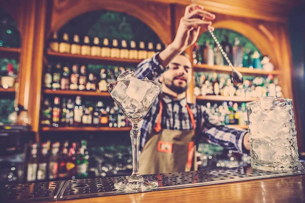 Barman haciendo un cóctel alcohólico en el mostrador del bar en el fondo del bar — Foto de Stock