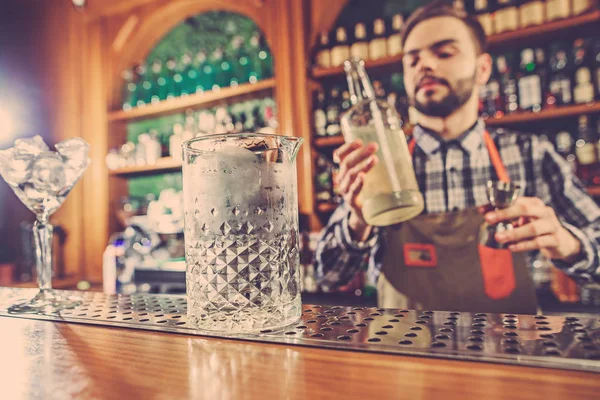 Barman haciendo un cóctel alcohólico en el mostrador del bar en el fondo del bar — Foto de Stock