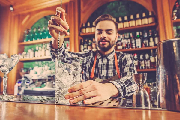 Barman haciendo un cóctel alcohólico en el mostrador del bar en el fondo del bar — Foto de Stock