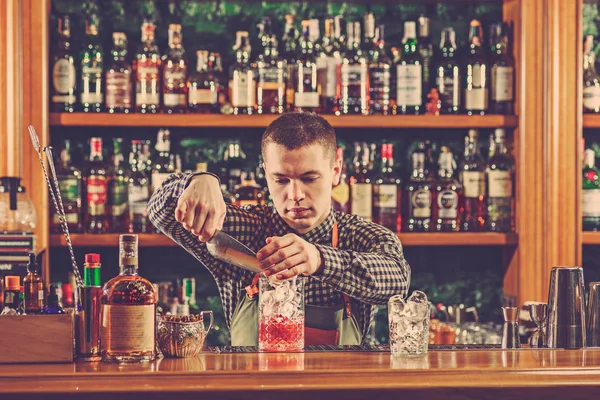 Barman haciendo un cóctel alcohólico en el mostrador del bar en el fondo del bar —  Fotos de Stock