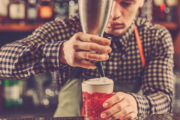 Barman haciendo un cóctel alcohólico en el mostrador del bar en el fondo del bar — Foto de Stock