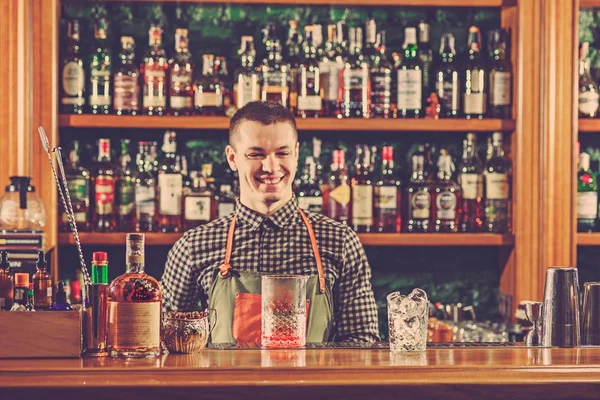 Barman ofrece un cóctel alcohólico en el mostrador del bar en el fondo del bar — Foto de Stock