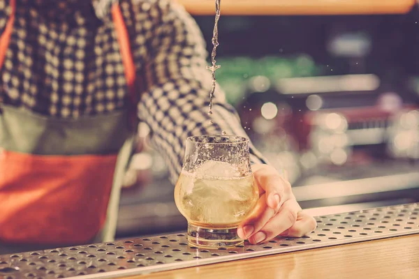 Barman haciendo un cóctel alcohólico en el mostrador del bar en el fondo del bar — Foto de Stock