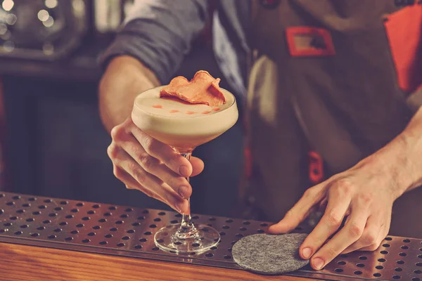 Barman ofrece un cóctel alcohólico en el mostrador del bar en el fondo del bar — Foto de Stock