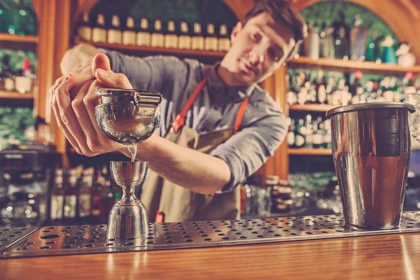 Expert barman is making cocktail at night club.