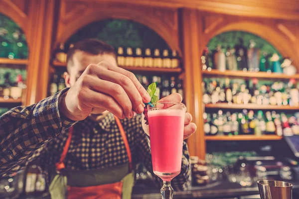 Barman haciendo un cóctel alcohólico en el mostrador del bar en el fondo del bar — Foto de Stock