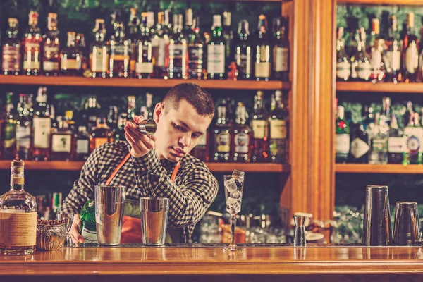 Barman haciendo un cóctel alcohólico en el mostrador del bar en el fondo del bar — Foto de Stock