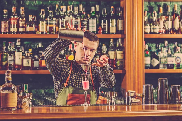 Barman haciendo un cóctel alcohólico en el mostrador del bar en el fondo del bar — Foto de Stock