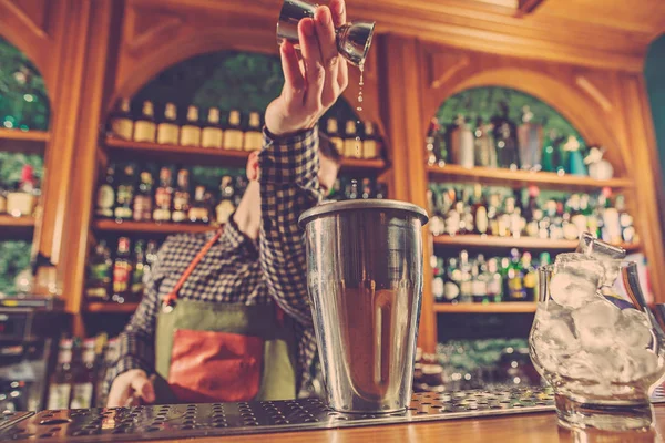 Barman haciendo un cóctel alcohólico en el mostrador del bar en el fondo del bar — Foto de Stock