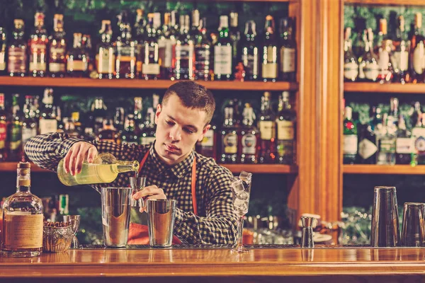 Barman haciendo un cóctel alcohólico en el mostrador del bar en el fondo del bar — Foto de Stock