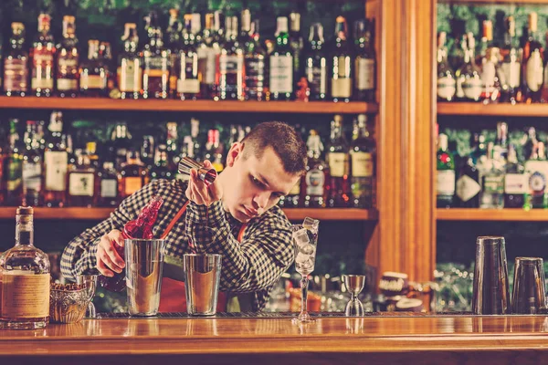 Barman haciendo un cóctel alcohólico en el mostrador del bar en el fondo del bar — Foto de Stock