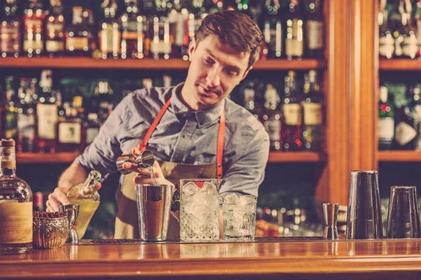 Expert barman is making cocktail at night club.