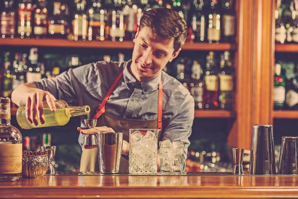 Expert barman is making cocktail at night club.