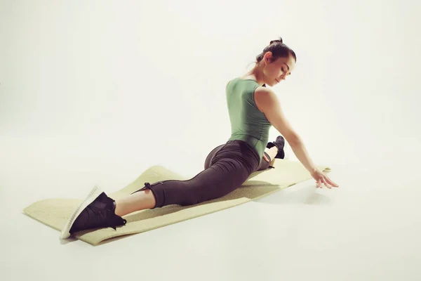 Hermosa morena delgada haciendo algunos ejercicios de estiramiento en un gimnasio —  Fotos de Stock