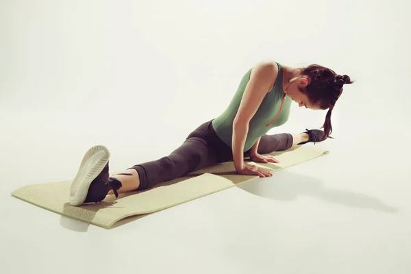 Mooie slanke brunette doen sommige stretching oefeningen in een sportschool — Stockfoto