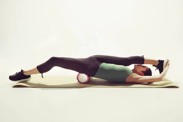 Beautiful slim brunette doing some stretching exercises in a gym — Stock Photo, Image