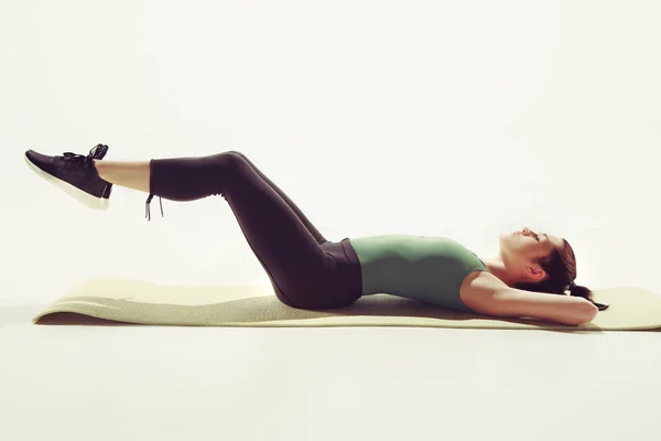Vacker smal brunett gör några stretching övningar i ett gym — Stockfoto