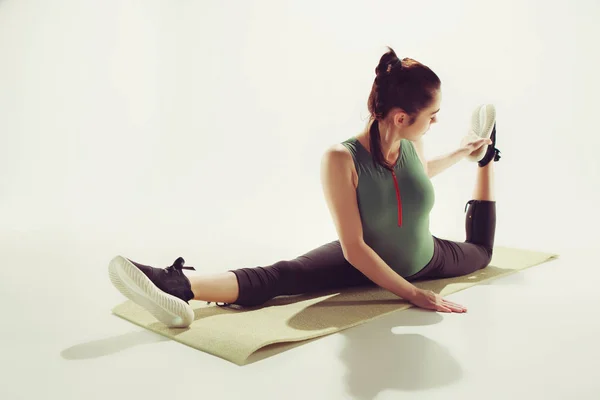 Mooie slanke brunette doen sommige stretching oefeningen in een sportschool — Stockfoto