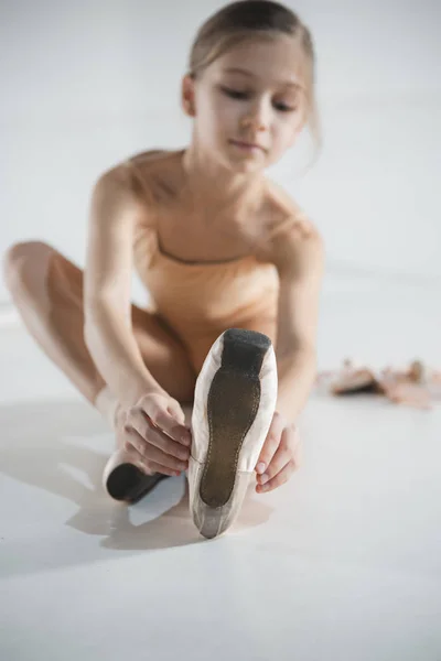 Mooie kleine ballerina in blauwe jurk voor dansen voet pointe schoenen zetten — Stockfoto