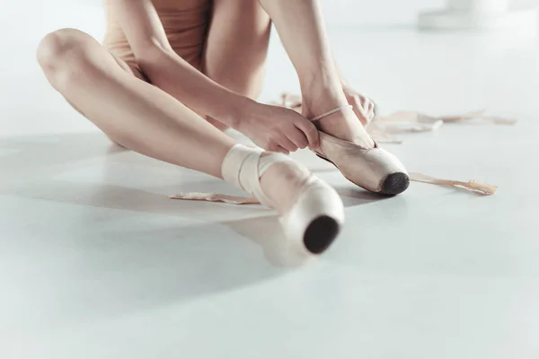 Beautiful little ballerina puting on foot pointe shoes — Stock Photo, Image