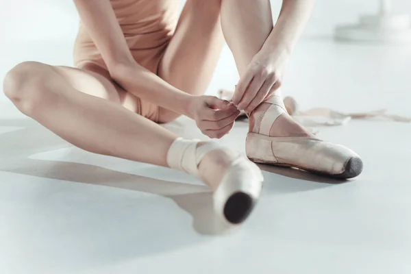 Beautiful little ballerina puting on foot pointe shoes — Stock Photo, Image
