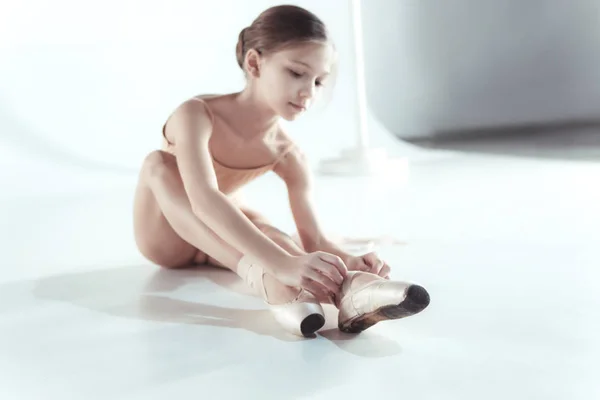 Красивая маленькая балерина, натягивающая пуанты для ног — стоковое фото