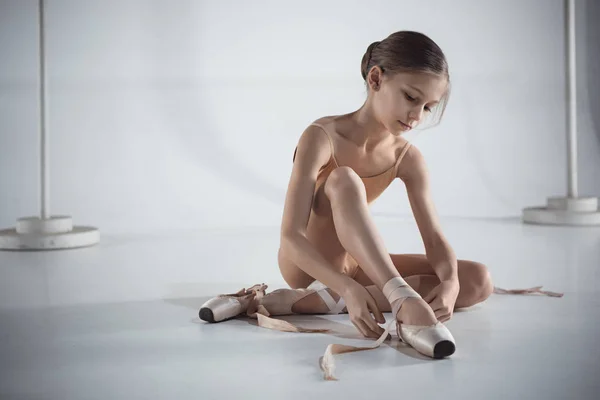 Beautiful little ballerina puting on foot pointe shoes — Stock Photo, Image