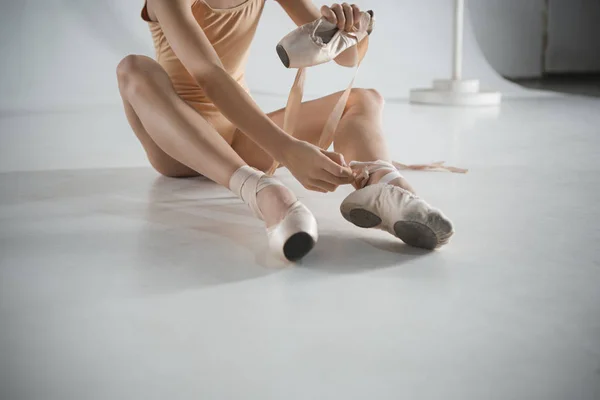 Beautiful little ballerina puting on foot pointe shoes — Stock Photo, Image