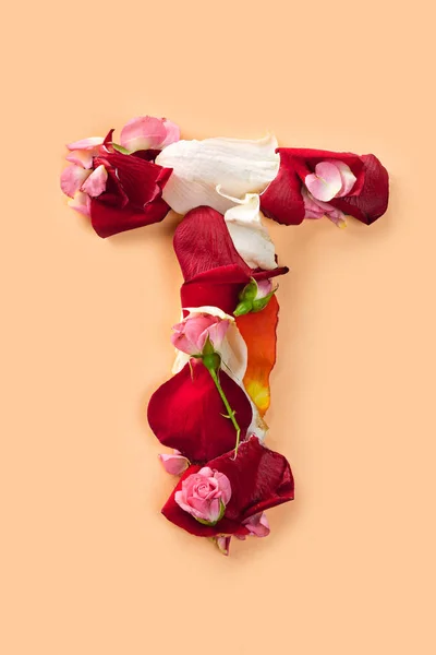 T の文字が赤いバラから作られたと、白い背景で隔離の花びら — ストック写真