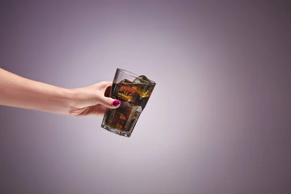 Пийте колу в склянці з рукою на бузковому фоні . — стокове фото