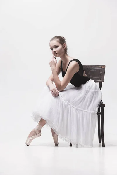 Молодая балерина в белом рюкзаке сидит на стуле — стоковое фото