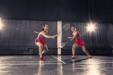 Genç kadın spor salonunda badminton oynarken