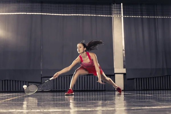 Ung kvinne som spiller badminton i gymsalen – stockfoto