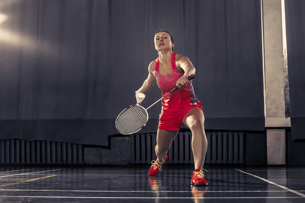 Ung kvinna spelar badminton på gym — Stockfoto