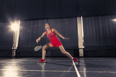 Genç kadın spor salonunda badminton oynarken