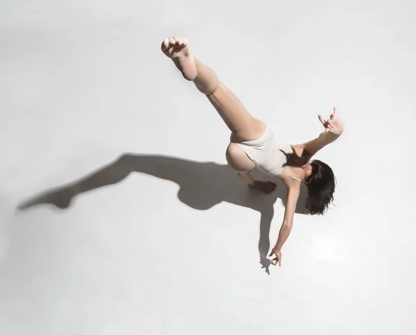 Молодий красивий танцюрист у бежевій сукні танцює на сірому фоні — стокове фото