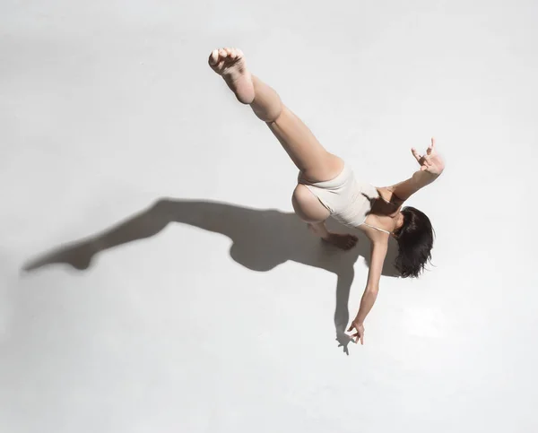 Joven hermosa bailarina en vestido beige bailando sobre fondo gris —  Fotos de Stock