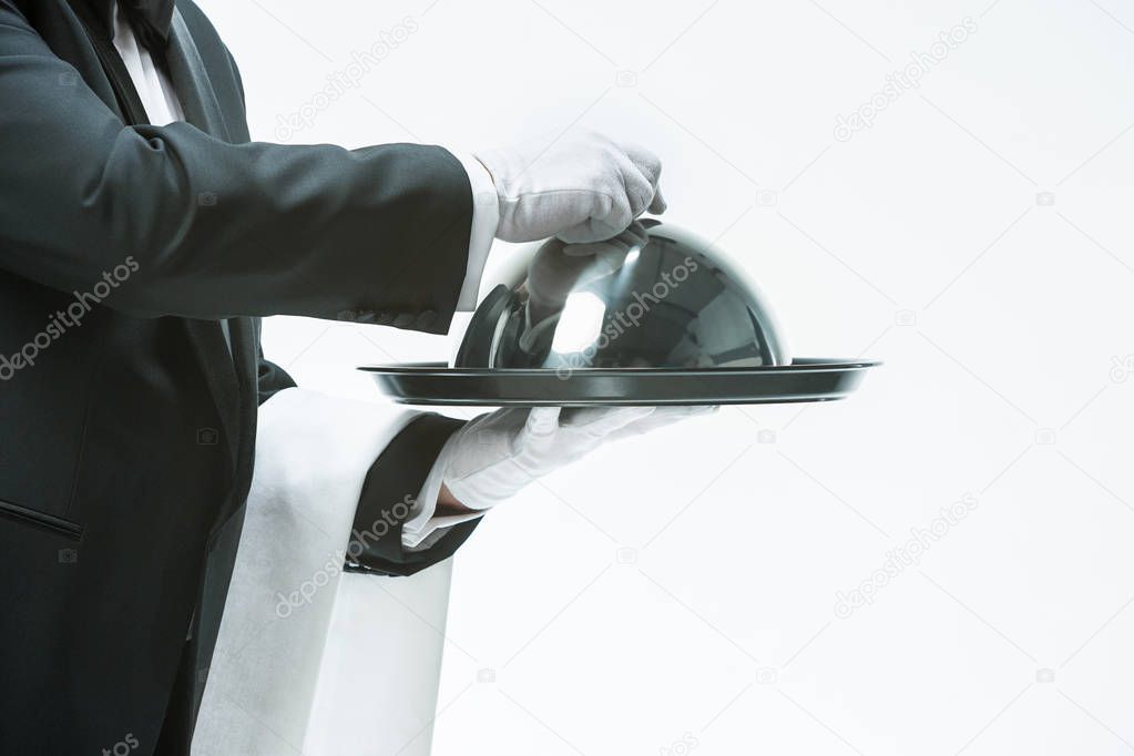 Close up waiter hand with tray and metal cloche lid cover