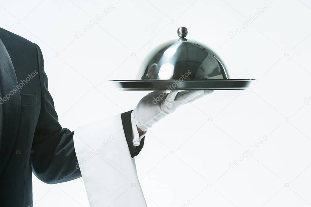 Close up waiter hand with tray and metal cloche lid cover