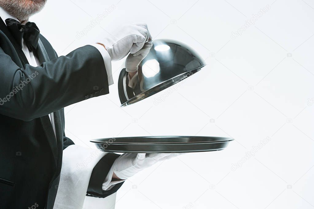 Close up waiter hand with tray and metal cloche lid cover