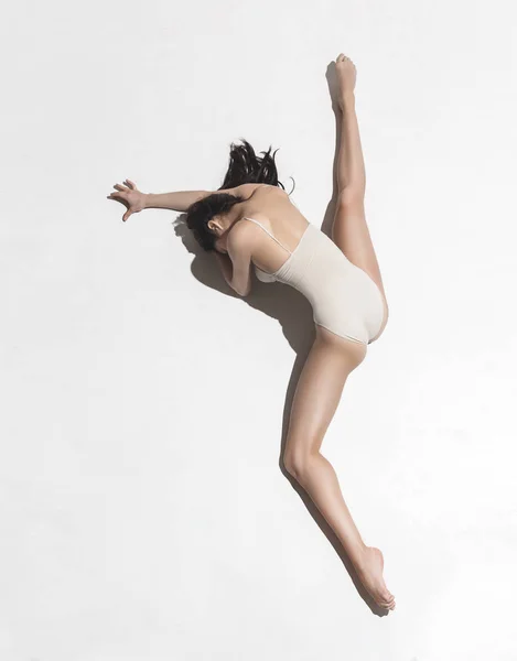 灰色の背景の上で踊ってベージュのドレスに若い美しいダンサー — ストック写真