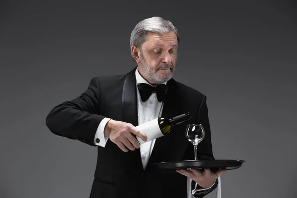 Ammattimainen tarjoilija univormussa tarjoilee viiniä — kuvapankkivalokuva
