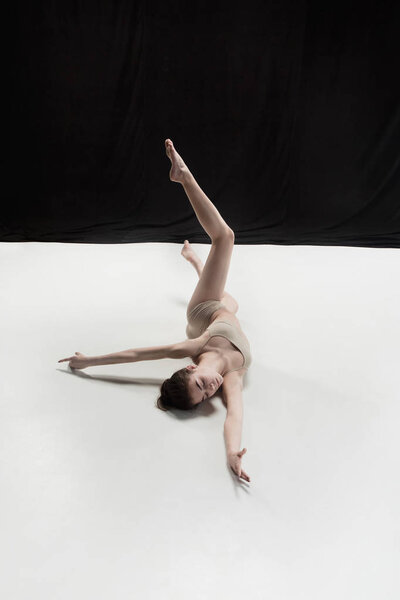 Young teen dancer dancing on white floor studio background. Ballerina project.