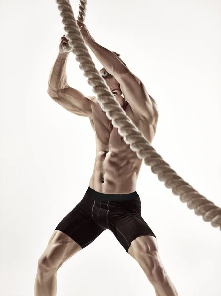 Attractive muscular man working out with heavy ropes. — Stock Photo, Image